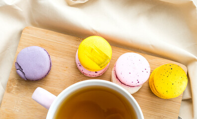 A cup of aromatic green tea and multi-colored macaroon cakes