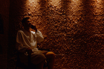 middle aged man relaxing in a salt room cave in spa. getting halotherapy treatment.