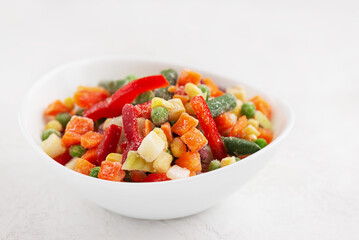 Frozen bell peppers, carrots, corn, peas, celery, onions and tomatoes in a white plate.