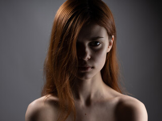 Woman model close-up naked shoulders red hair dark background