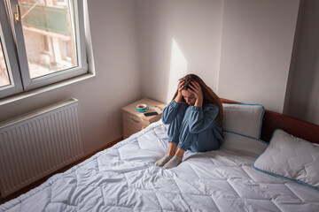 Upset woman holding head in hands depressed in bed