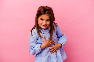 Little caucasian girl isolated on pink background  laughs happily and has fun keeping hands on...