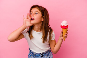 Little caucasian girl holding ice cream isolated on pink background shouting and holding palm near opened mouth.