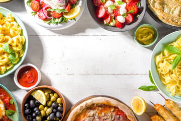 Set of different Mediterranean foods: olives, mozzarella and tomato salad, Greek salad, pasta, tortellini ravioli, pizza, pita lavash sandwich, shish kebab, shakshuka, hummus, top view