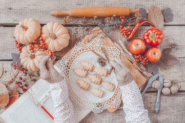Senior woman wrinkled hands top view, cooking process. Christmas, autumn holiday, bakery, fruits, vegetables, wooden table, old book recipes. Sharing family tradition. Healthy, thanksgiving food.