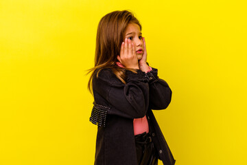Little caucasian girl isolated on yellow background scared and afraid.
