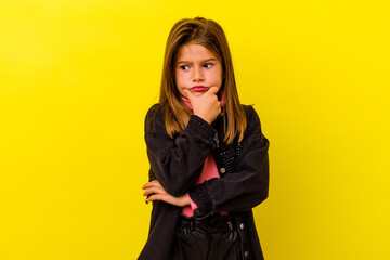 Little caucasian girl isolated on yellow background suspicious, uncertain, examining you.