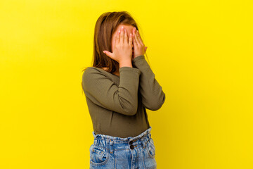 Little caucasian girl isolated on yellow background afraid covering eyes with hands.