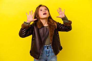 Little caucasian girl isolated on yellow background screaming to the sky, looking up, frustrated.