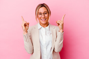 Young caucasian mixed race business woman isolated on pink background indicates with both fore...