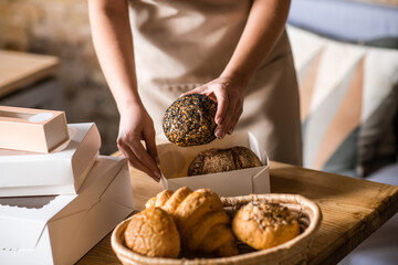 Female hands packing bread bun into box