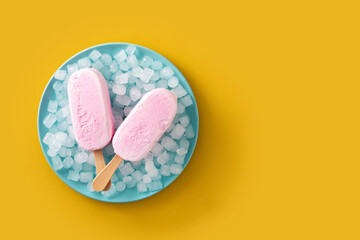 Strawberry popsicles and crushed ice on blue plate and yellow background.Top view. Copy space