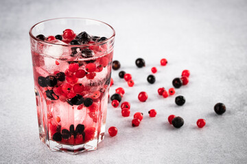 Glass of red currant. Refreshment summer drink with black currants and ice close-up on a gray background. Fruitarianism, veganism concept. Vegetarian diet. Berry lemonade. Colorful fruits.
