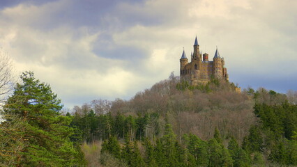 naher Blick auf Burg Hohenzollern umgeben von Wald auf der Schwäbischen Alb mit lebhaften Wolken
