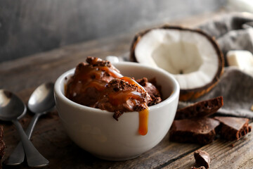 Chocolate coconut vegan ice cream in a white cup. Ice cream balls with chocolate and caramel....