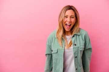 Young mixed race woman isolated on pink background shouting very angry, rage concept, frustrated.