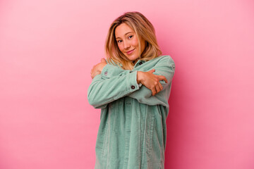 Naklejka premium Young mixed race woman isolated on pink background hugs, smiling carefree and happy.