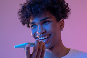 Curly-haired smiling guy recording a voice message and smiling