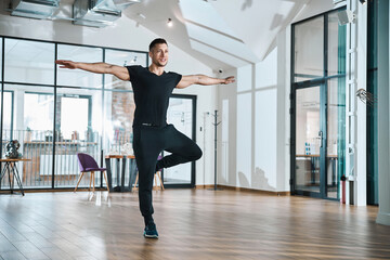 Fototapeta na wymiar Sportive man standing in yoga pose with spread arms