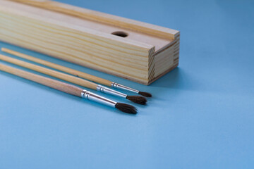 Paint brushes and brush case on a light blue background. Painting tools.