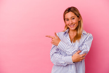 Young mixed race woman isolated on pink background smiling cheerfully pointing with forefinger away.