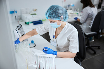 Biochemist with a vacutainer sitting at a lab table