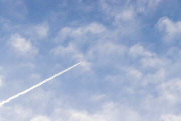 春の朝の美しい飛行機雲と白いくも、青い空