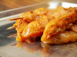 Marinated raw chicken pieces on a wooden skewer on a metal surface. Summer barbeque range product. Asian style sous over poultry meat. Ready made kebab