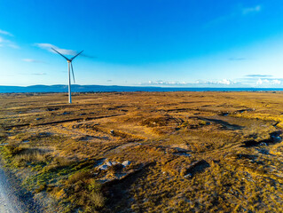 White wind turbine with propellers in a field. Aerial drone view, Clean blue sky, Sunrise time....