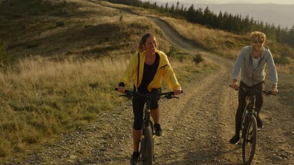 Woman and man cycling on mountain road. Athletes riding sport bikes outdoor