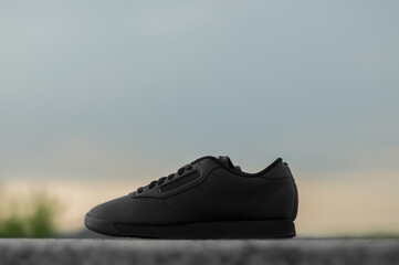 Black sneakers on sky background