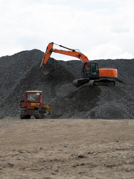 A heavy excavator and a bulldozer are working in a crushed stone factory.