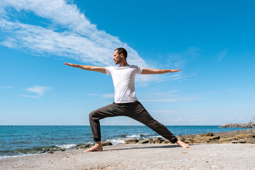 Attractive young man practicing yoga meditation and breathwork outdoors by the sea