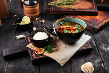 Asian spicy soup with rice on the wooden background