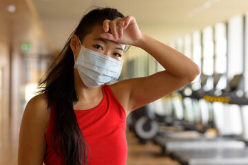 Asian woman wearing surgical medical face mask to protect from corona virus and workout at gym