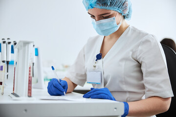 Biochemist in latex gloves analyzing the patient blood test results