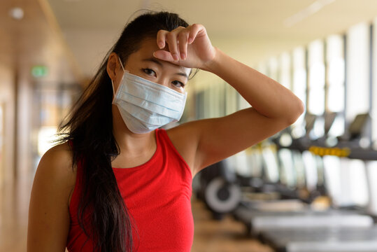 Asian woman wearing surgical medical face mask to protect from corona virus and workout at gym