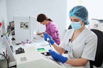 Fototapeta premium Young lab worker performing a biochemical analysis in latex gloves