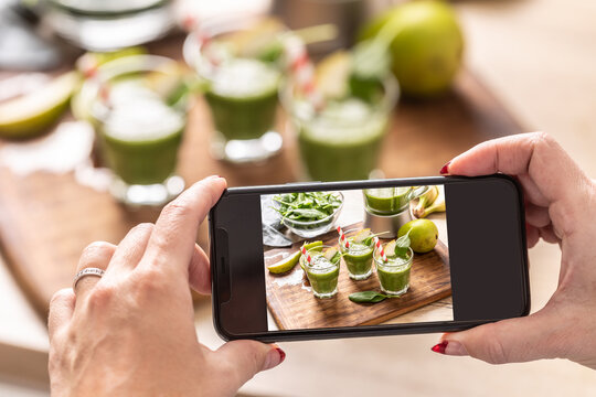Blogger woman making photo of smoothie with cell phone