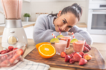 Obraz na płótnie Canvas Good looking woman enjoying her home made fruit smoothies in the kitchen