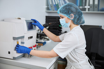 Experienced biochemist using a hematology analyzer for a blood analysis