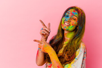 Young Indian woman celebrating holy festival isolated on white background excited pointing with...