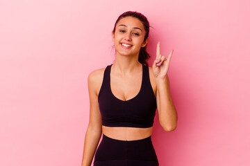 Young sport Indian woman isolated on pink background showing a horns gesture as a revolution concept.