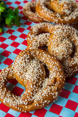 Freshly baked homemade soft pretzels with sesame seeds and garlic flakes, ready to eat and hot from the oven. Tasty gluten free savory pastry with a knot on a vibrant, colorful, background.