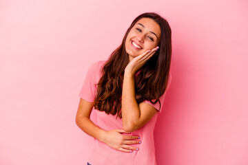 Young Indian woman isolated on pink background laughs happily and has fun keeping hands on stomach.