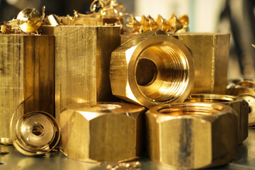Brass products turned from a hexagonal blank on a metal-working machine. Metal cutting in production. 