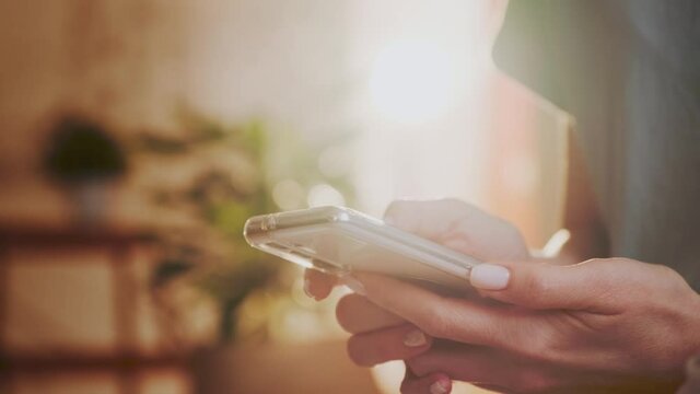 Woman Using Smartphone Sitting on The Floor in Bright Room on Sunny Day.