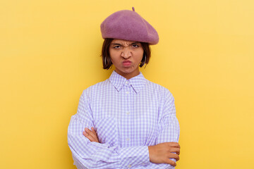Young mixed race woman wearing a beret isolated on yellow background frowning face in displeasure, keeps arms folded.