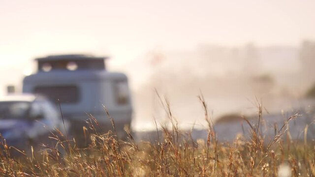 Coastal landscape with caravan trailer wild camping on beach. Capi Corb, Mediterranean coast of Spain. Holidays, traveling with motorhome. Focus on grass