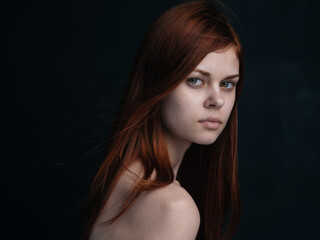 Portrait of a woman with red hair on a black background naked shoulders model
